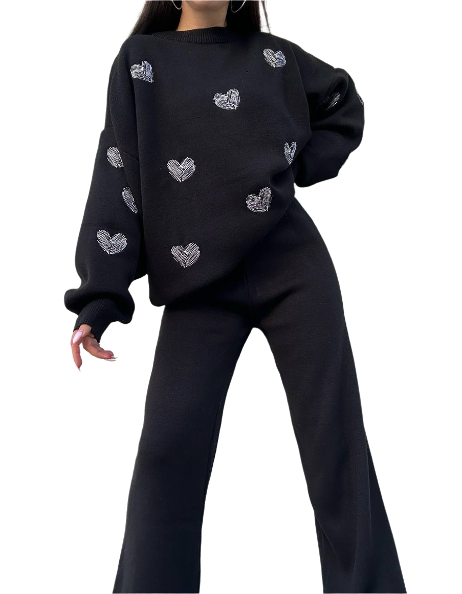 Person wearing a black sweater with heart patterns on a white background
