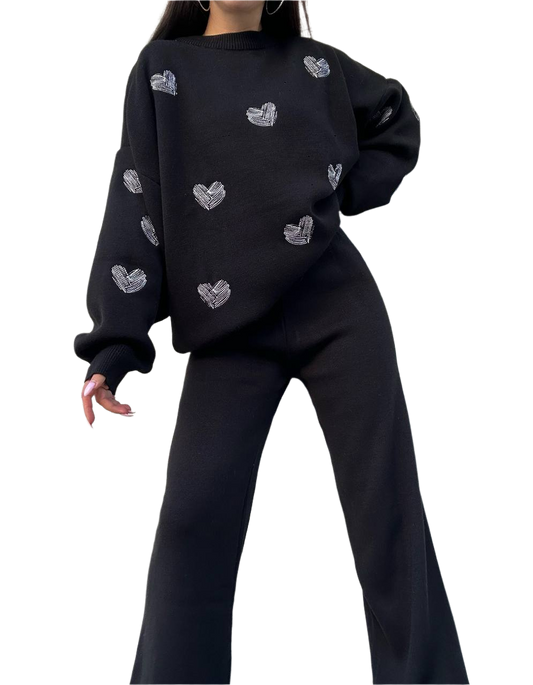 Person wearing a black sweater with heart patterns on a white background