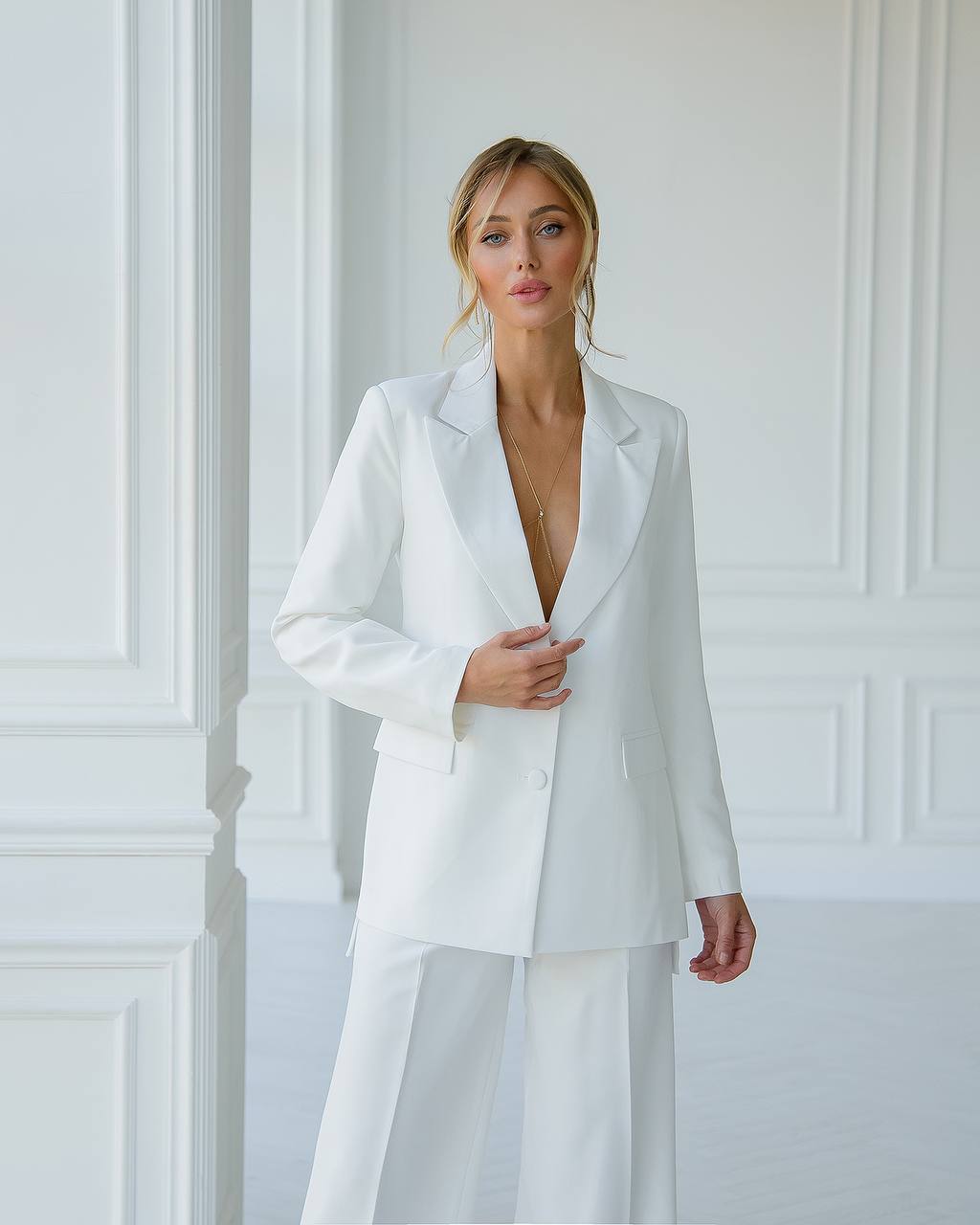 Woman wearing a white suit against a white wall