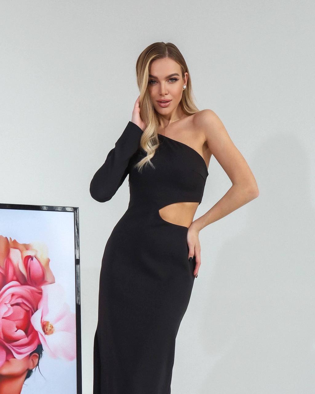 Woman wearing a black one-shoulder dress against a plain background