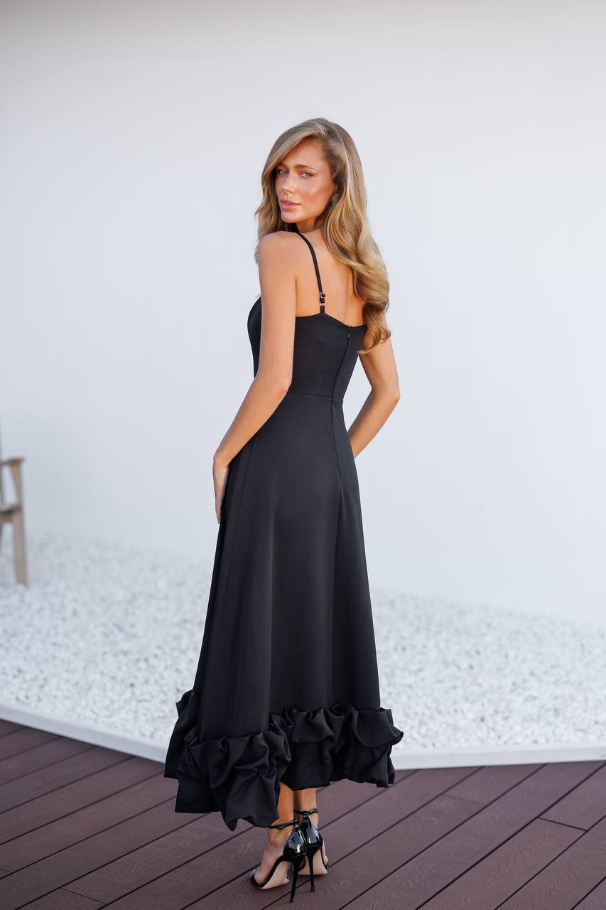 Woman wearing a black dress with ruffled hem on a wooden deck.