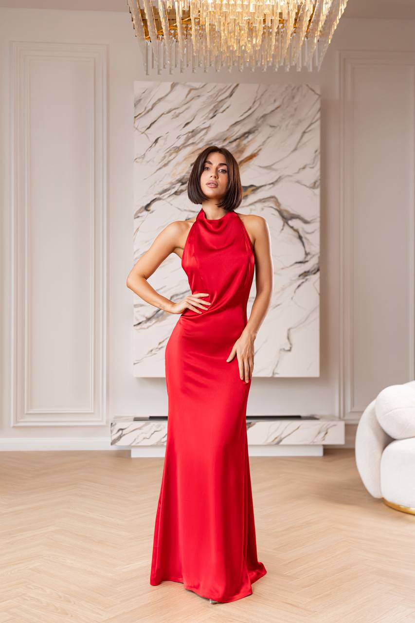 Woman in a red dress standing in an elegant room with marble wall art and chandelier.