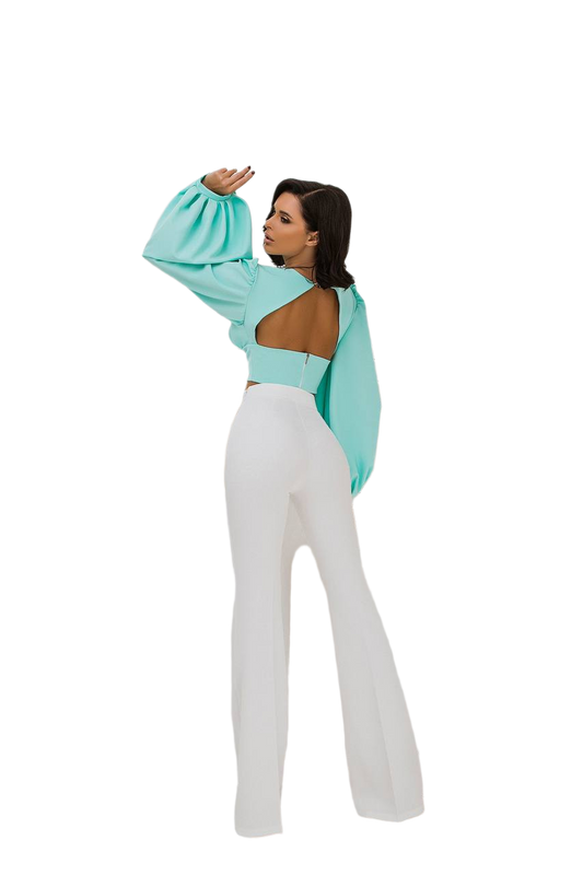 Woman wearing a light blue open-back top and white pants on a white background