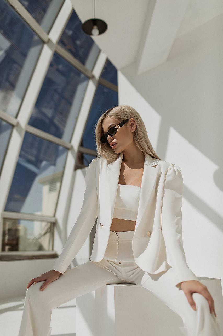 Woman in a white outfit sitting on a modern architectural structure.