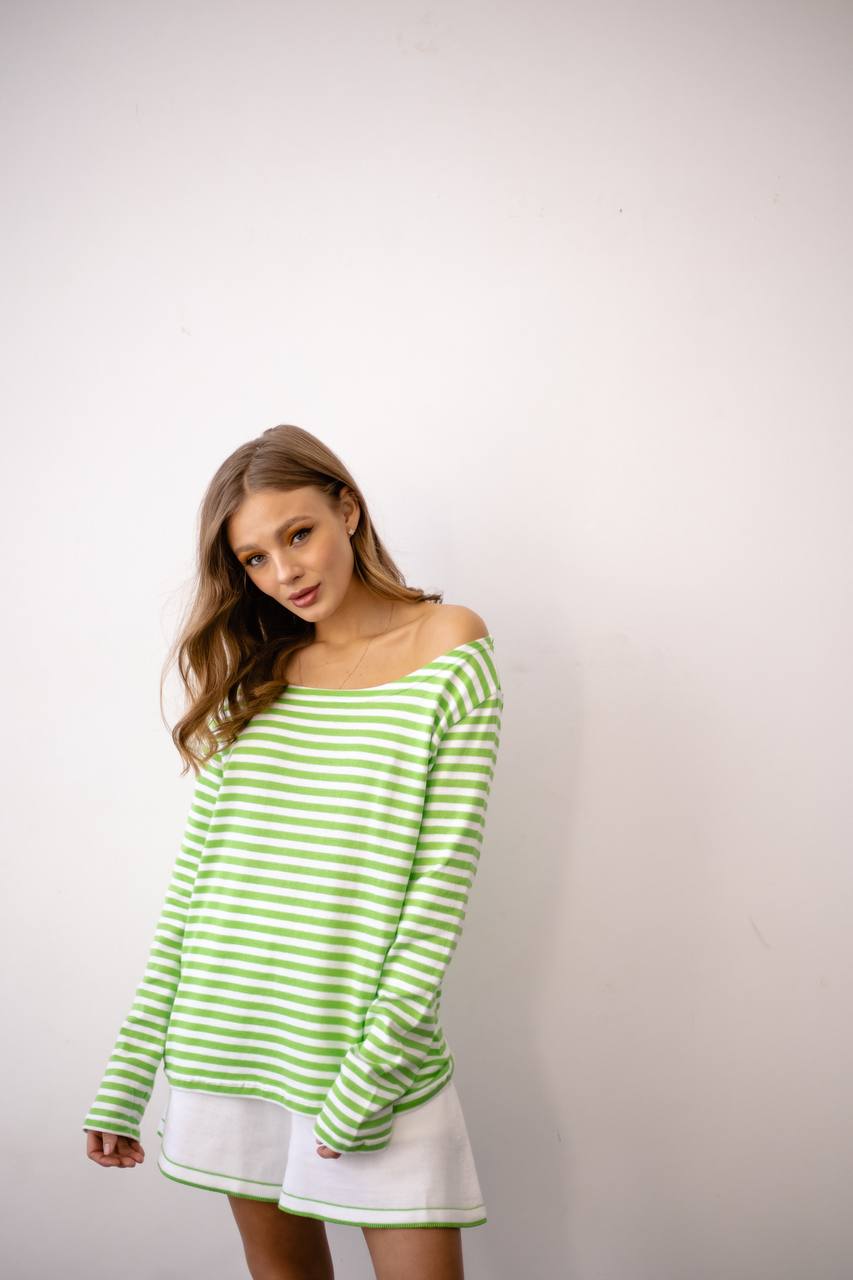Woman wearing a green and white striped sweater against a plain background