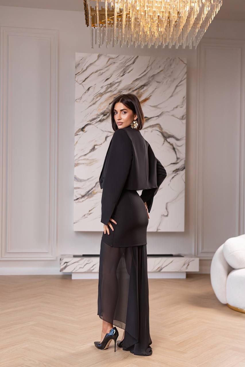 Woman in a black outfit standing in a stylish room with marble wall art and chandelier.