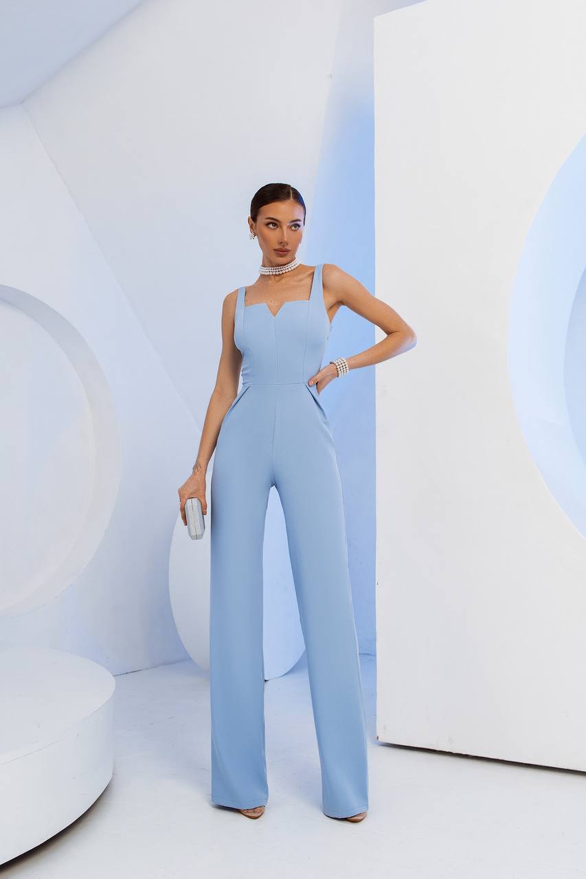 Woman wearing a light blue jumpsuit in a minimalistic setting