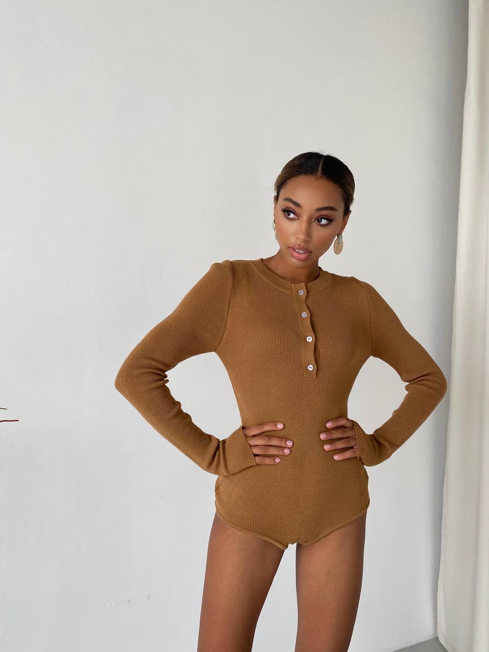 Woman wearing a brown bodysuit against a white background
