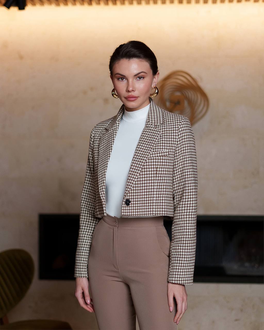 Woman wearing a checkered blazer and high-waisted pants in an indoor setting