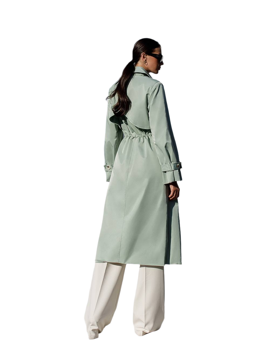 Person wearing a light green trench coat with a white background