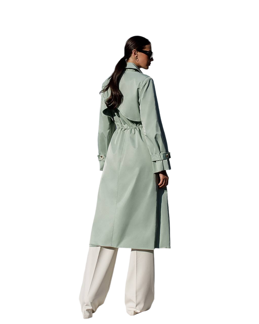 Person wearing a light green trench coat with a white background