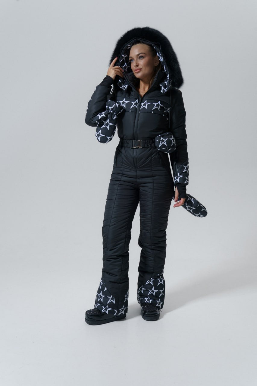 Person wearing a black snowsuit with star patterns on a white background