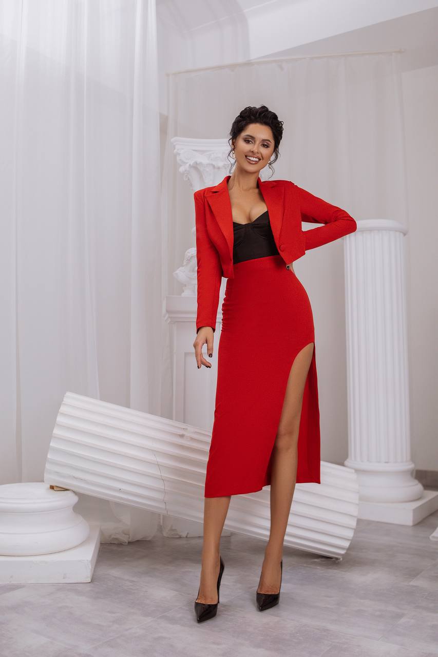 Woman in a red outfit standing in an elegant interior setting