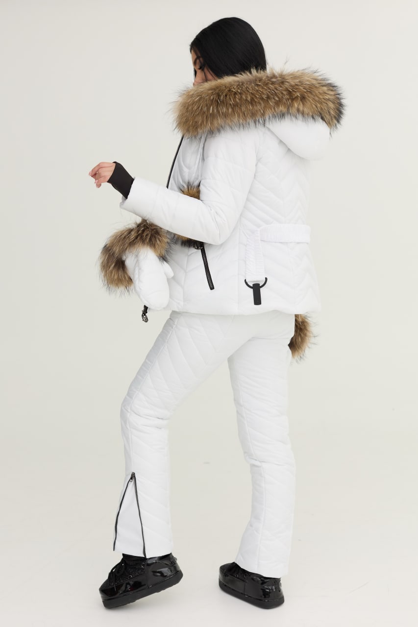 Person wearing a white winter coat with fur hood and white pants on a light gray background