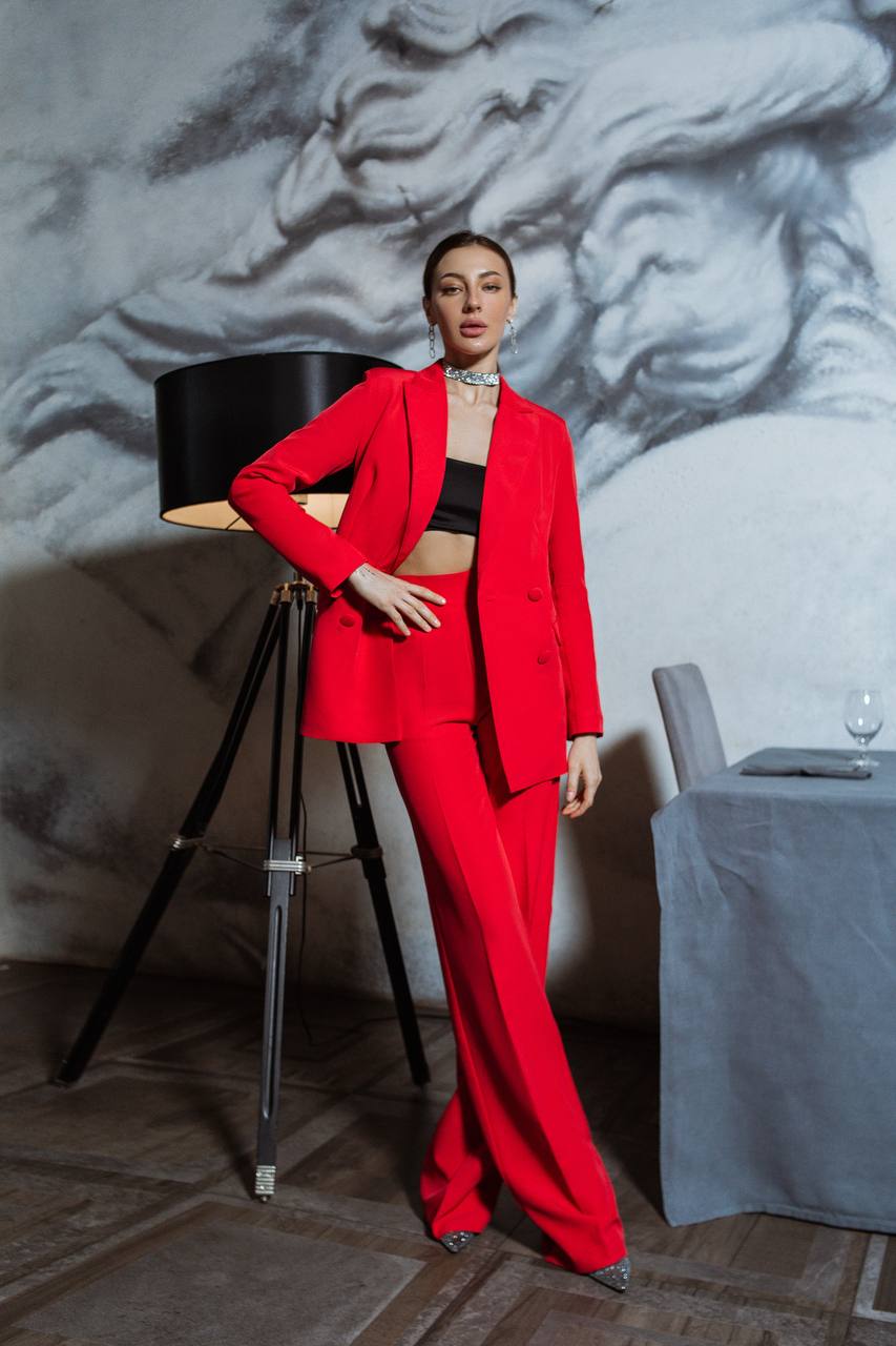 Person wearing a red outfit in an elegant room with a lamp and table.