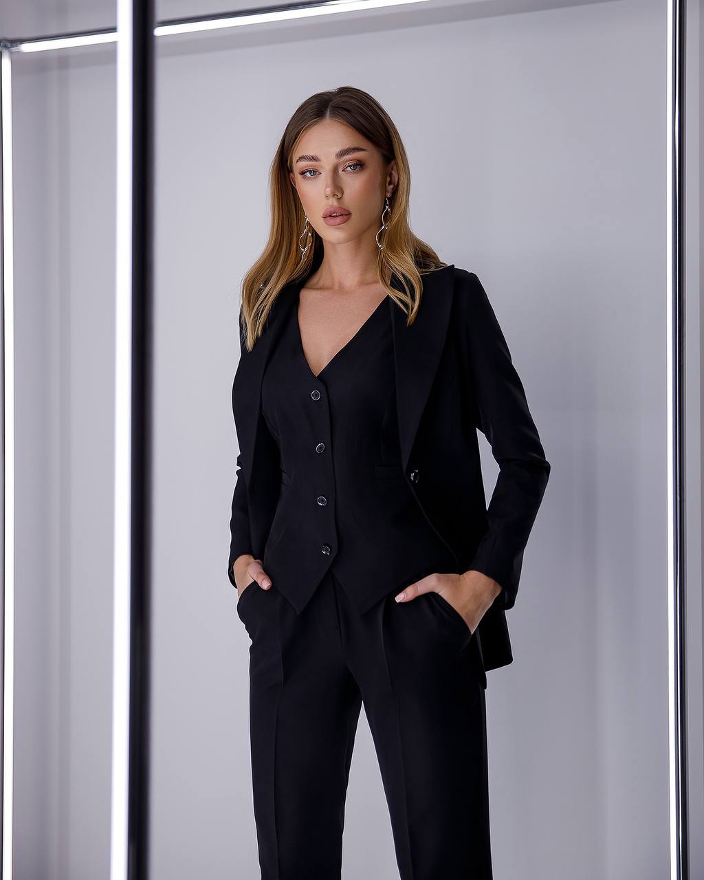 Woman wearing a black suit standing against a plain background