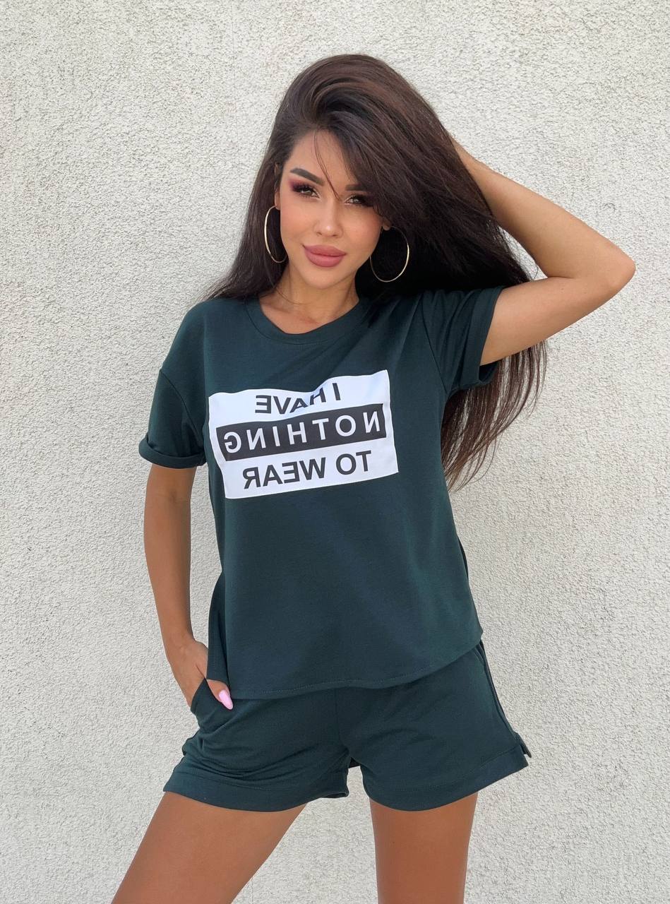 Woman wearing a dark green t-shirt with text and shorts against a light gray background