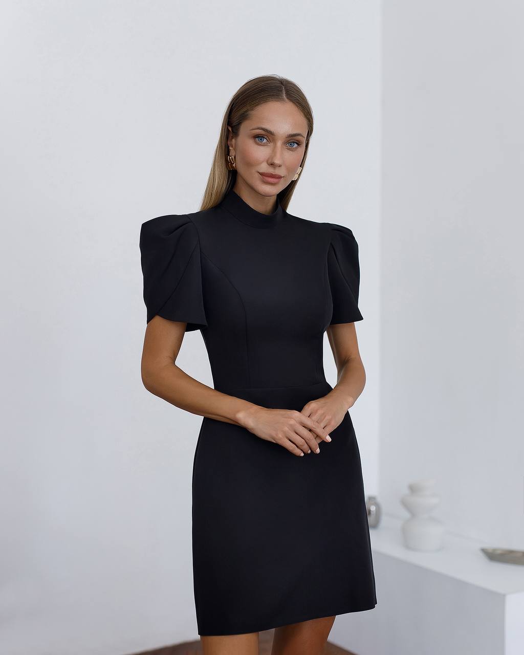 Woman wearing a black dress with puffed sleeves against a white background