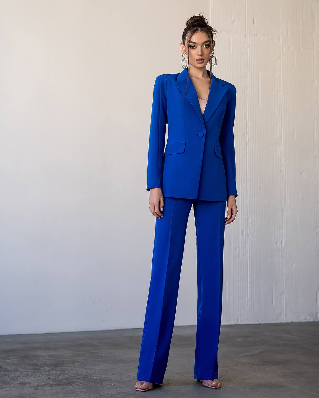 Woman wearing a blue suit standing against a plain background