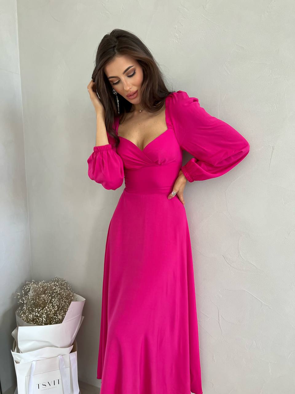 Woman wearing a bright pink dress with puffed sleeves against a plain background