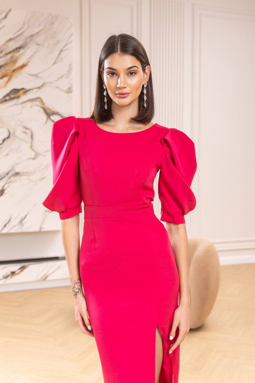 Woman wearing a bright pink dress with puffed sleeves in an indoor setting.