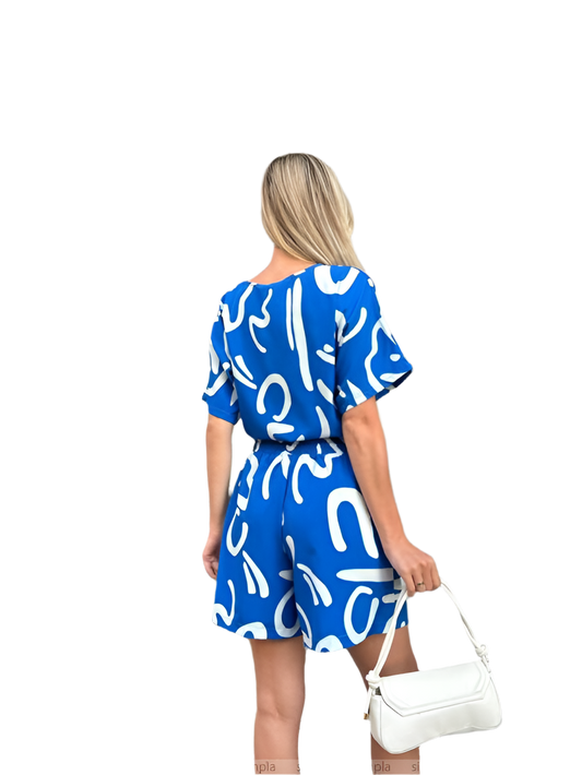 Woman wearing a blue dress with white patterns, holding a white handbag on a white background