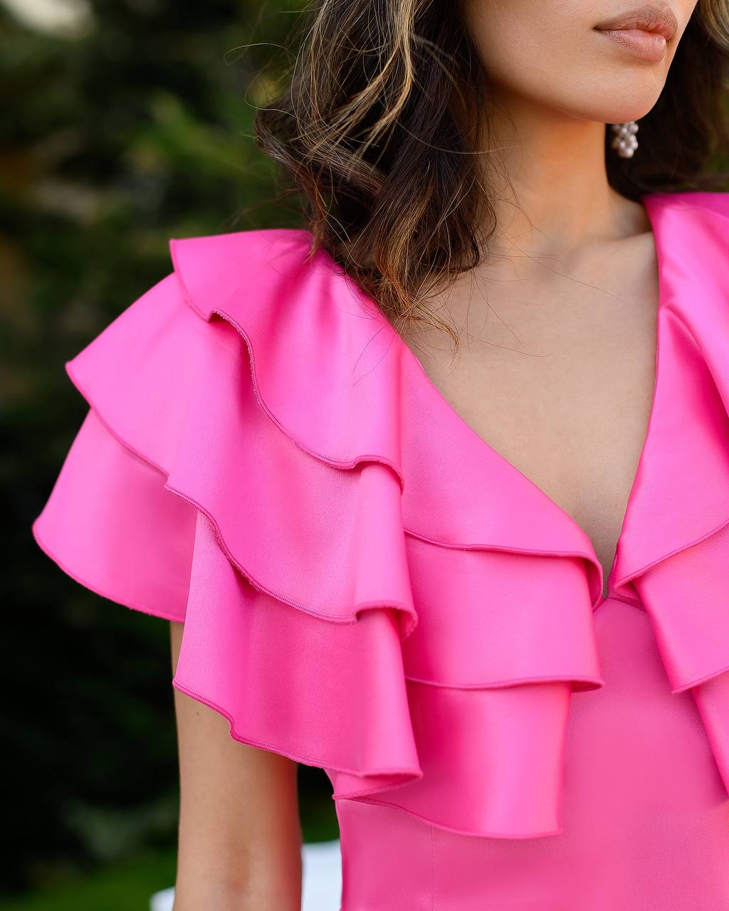 Close-up of a bright pink ruffled top worn by a person.