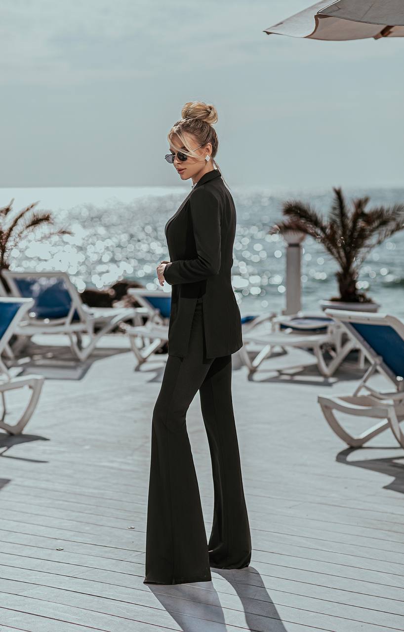 Woman in a black suit standing on a beach deck with ocean view