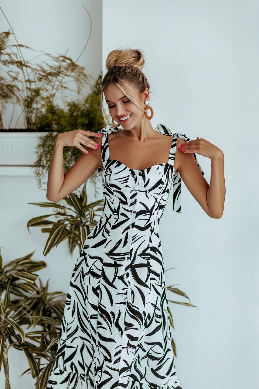 Woman wearing a black and white patterned dress with plants in the background