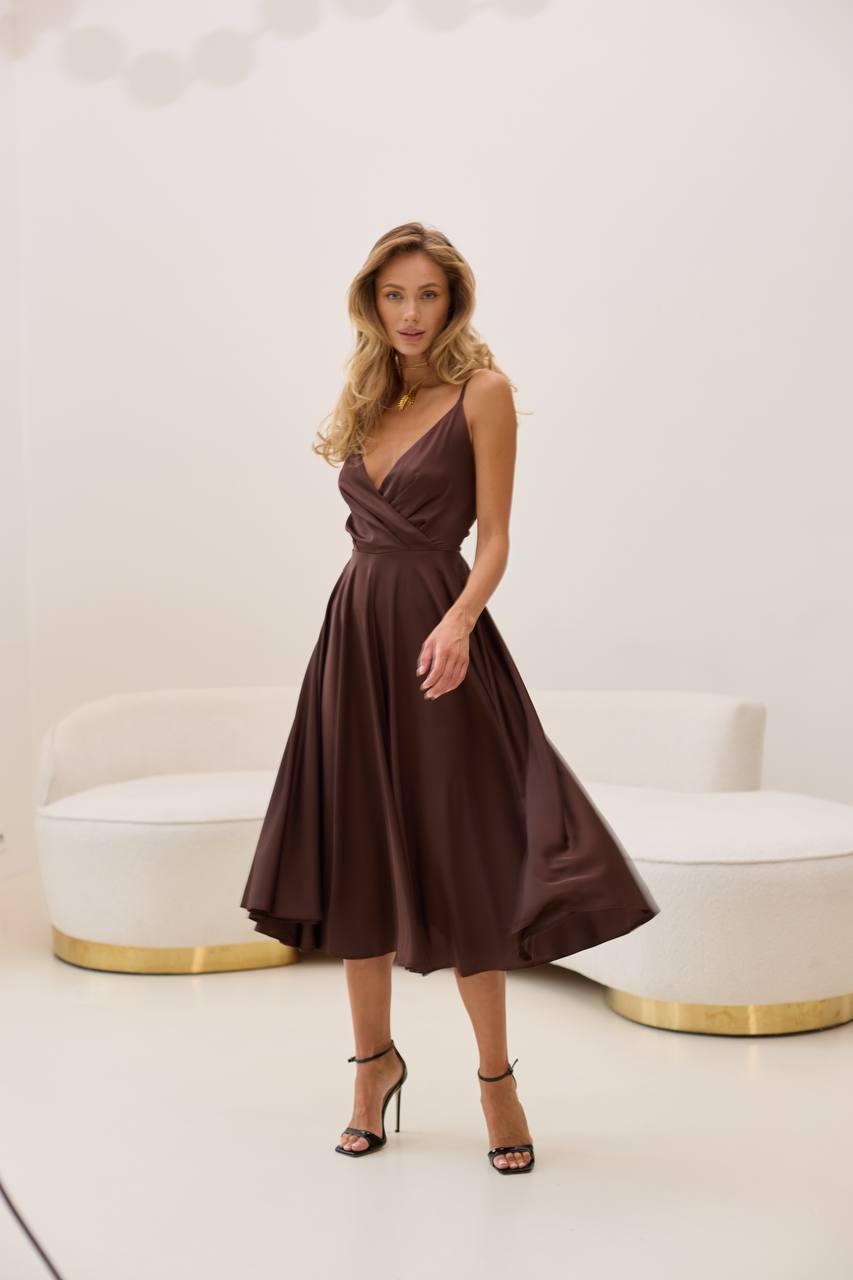 Woman wearing a brown dress standing in a modern interior setting