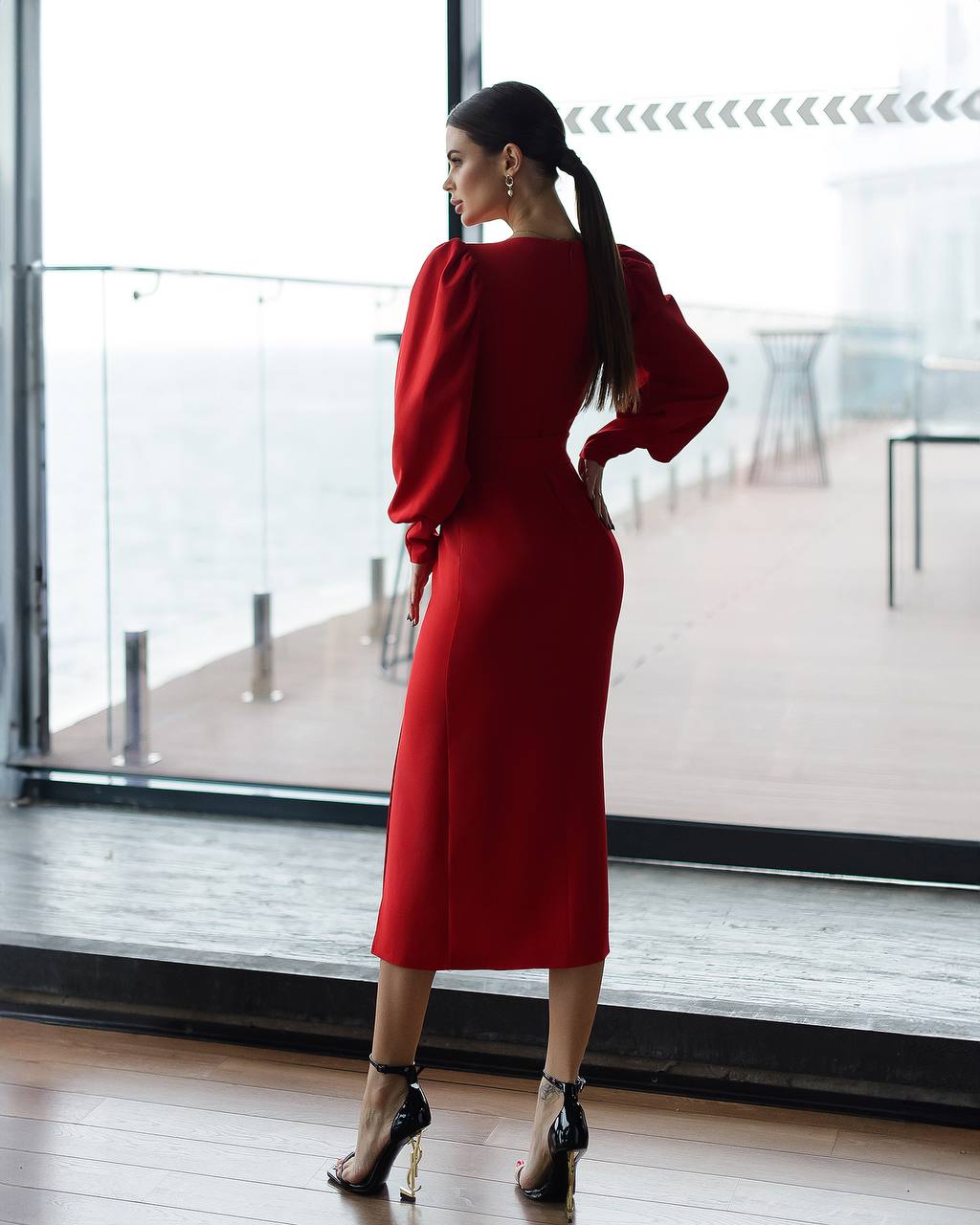 Woman in a red dress standing in front of a large window