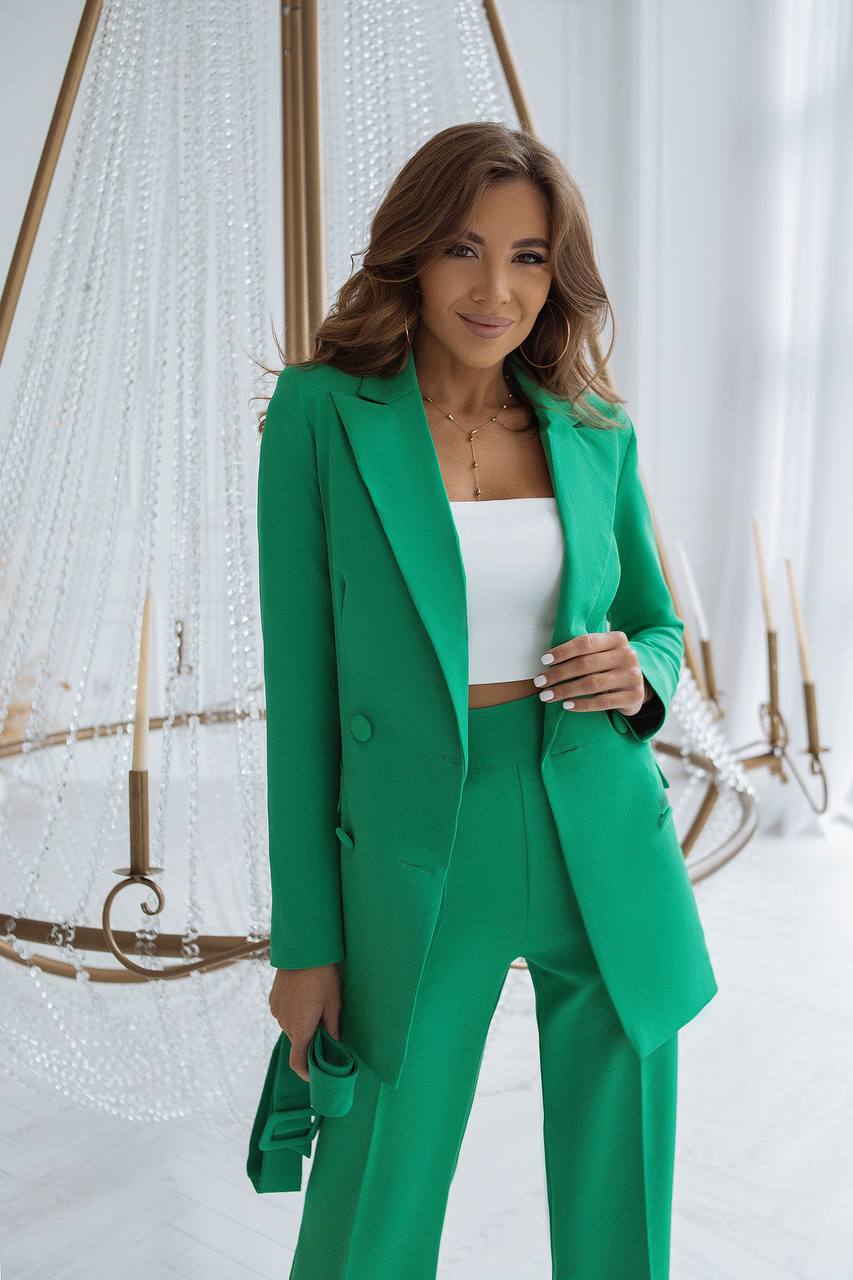 Woman wearing a green suit with a white top in a decorative setting