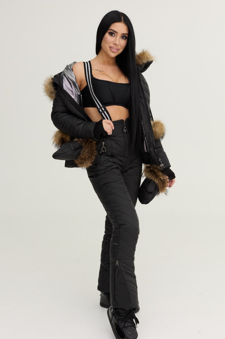 Woman wearing a black outfit with fur-lined hood against a white background