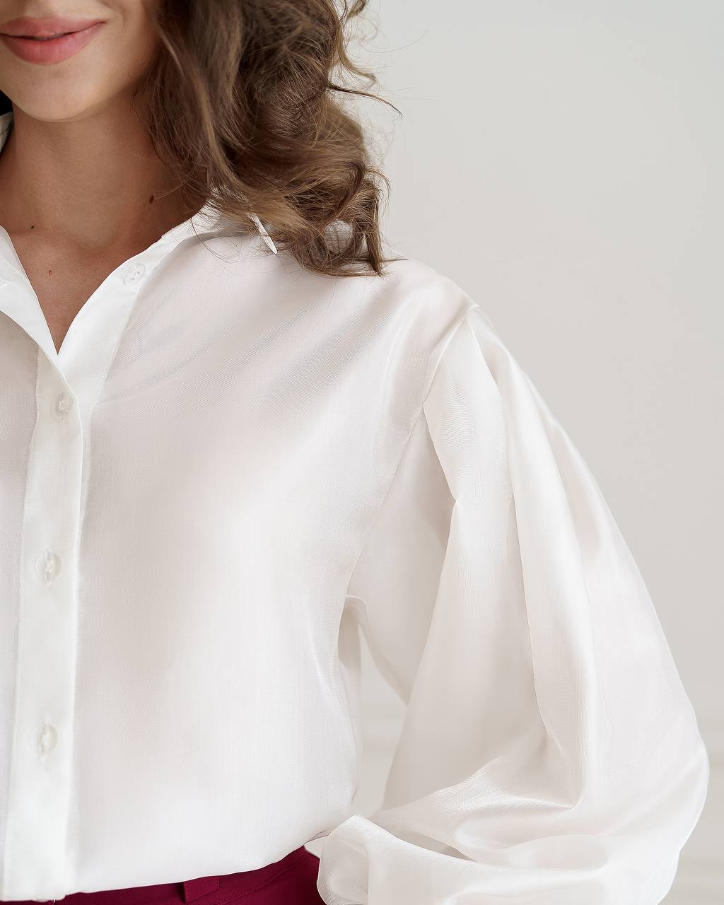 White blouse with long sleeves worn by a person on a plain background