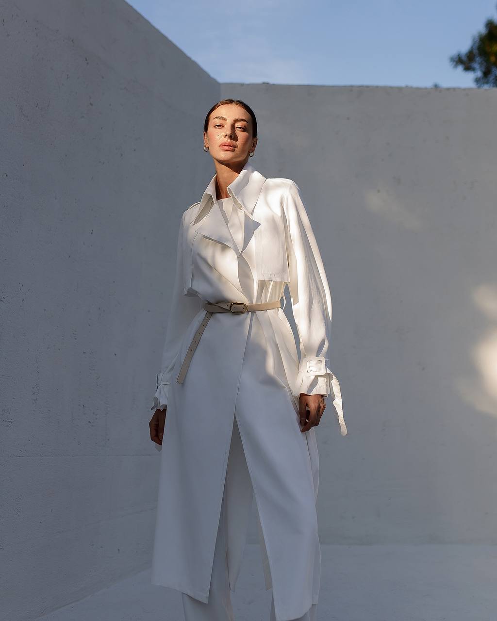 Person wearing a white outfit standing against a light-colored wall.