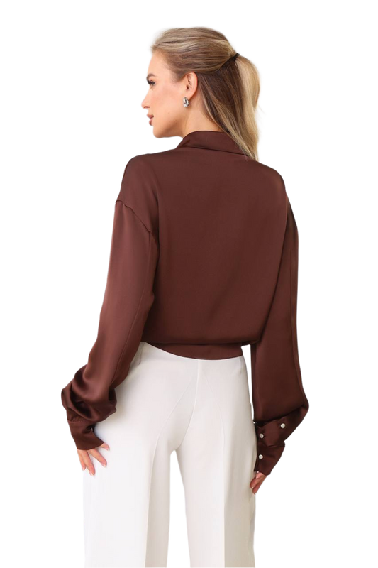 Woman wearing a brown blouse with long sleeves and a high collar on a white background