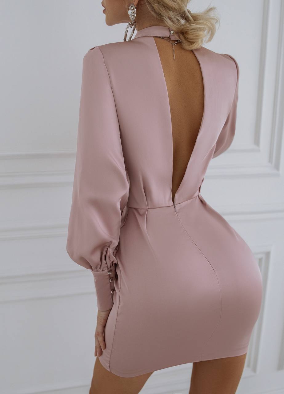 Pink dress with open back worn by a model against a white wall
