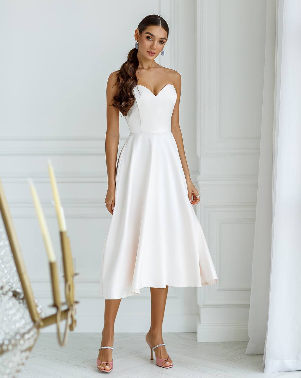 Woman wearing a white strapless dress in a minimalistic setting