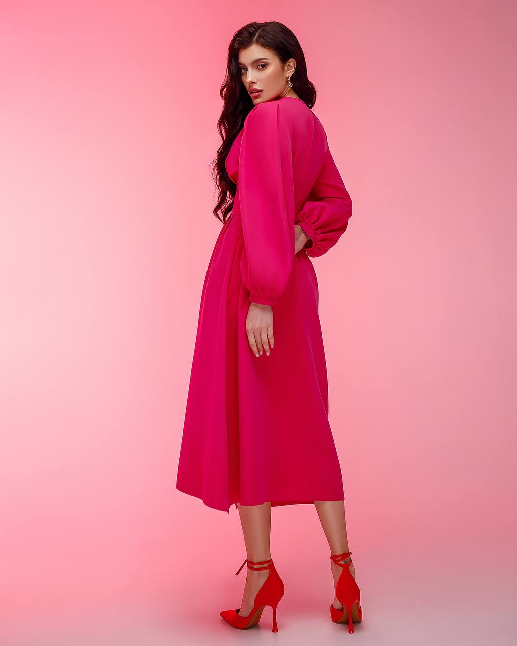 Woman wearing a bright pink dress against a pink background