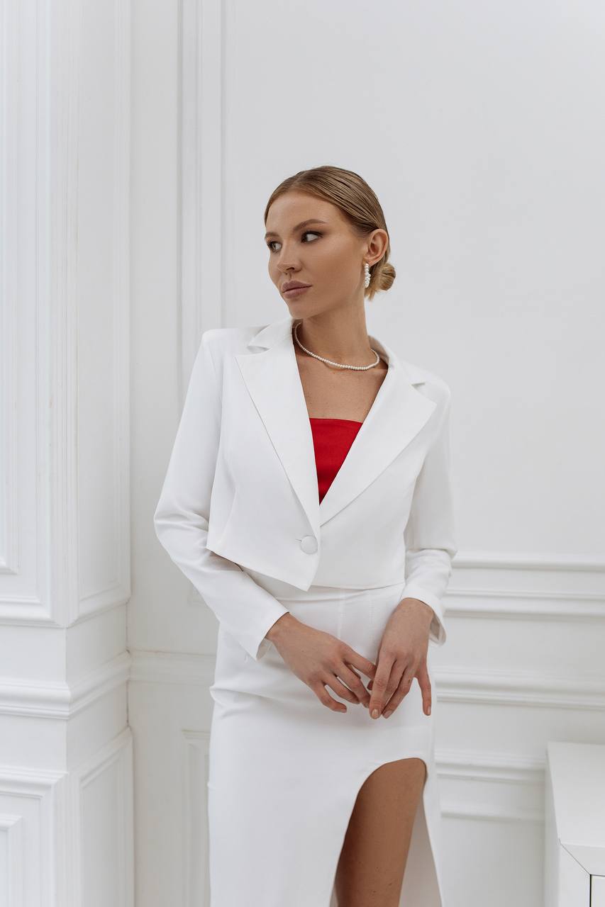 Woman in a white outfit with a red top against a white wall