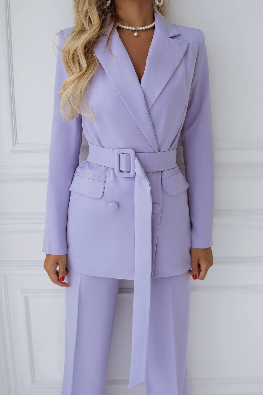 Person wearing a lavender suit with a belt against a white background