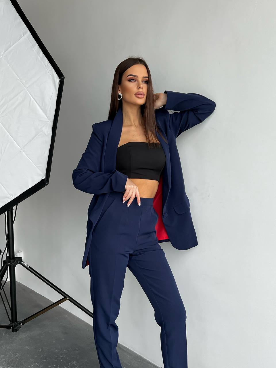 Woman in a navy blue suit posing in a studio setting
