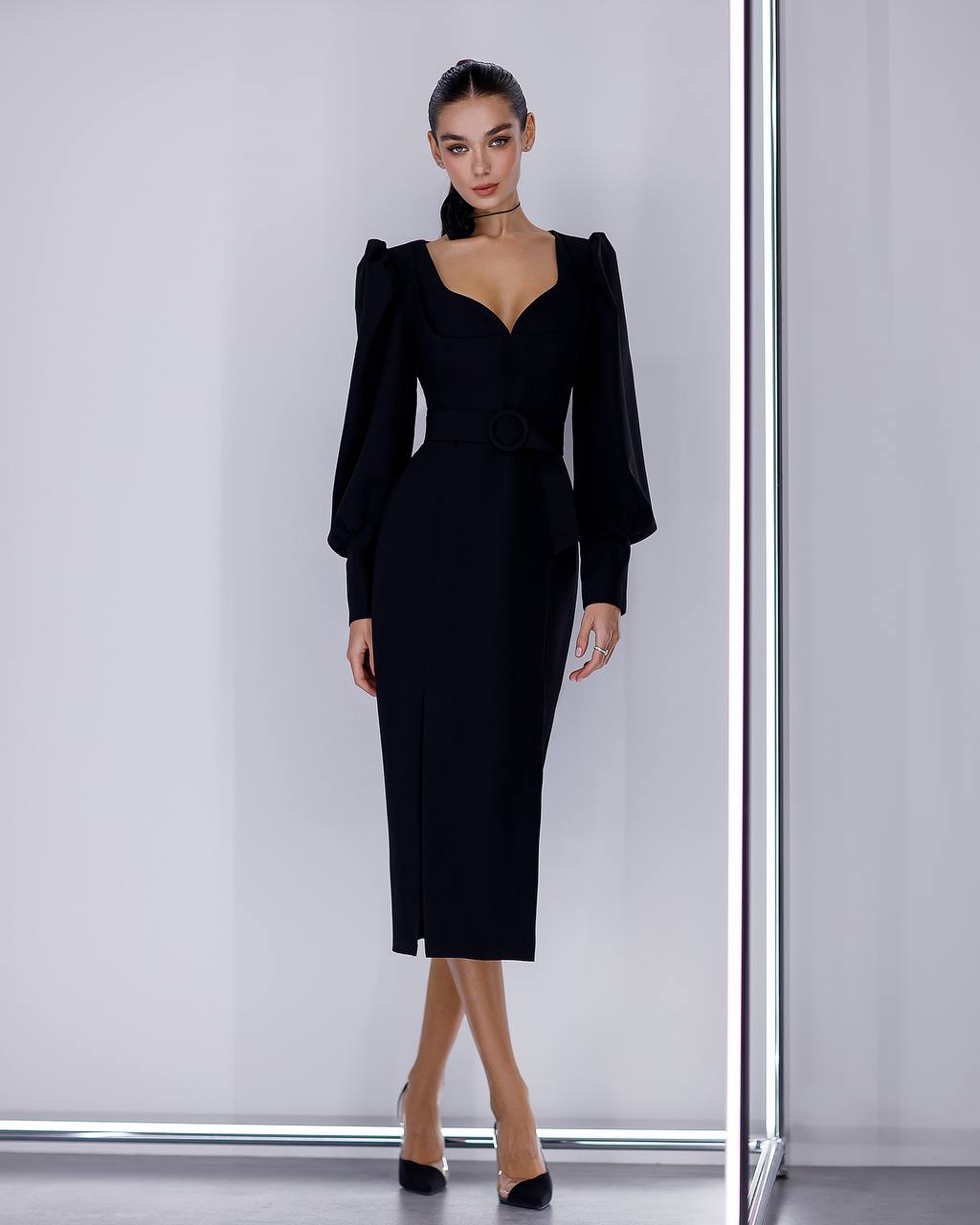 Woman wearing a black dress with puffed sleeves against a white background