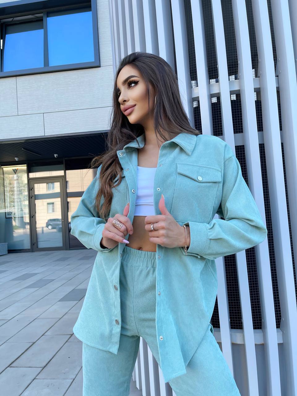 Woman in a light blue outfit standing outside a modern building.