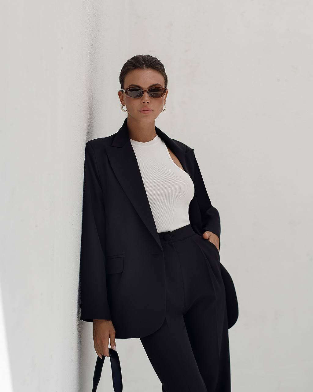Person wearing a black suit and white top against a plain background