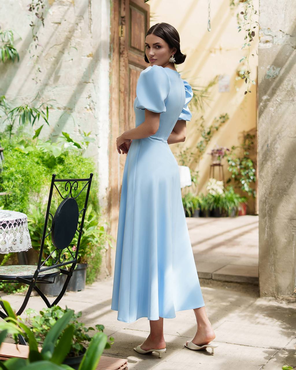Woman in a light blue dress standing in a garden setting
