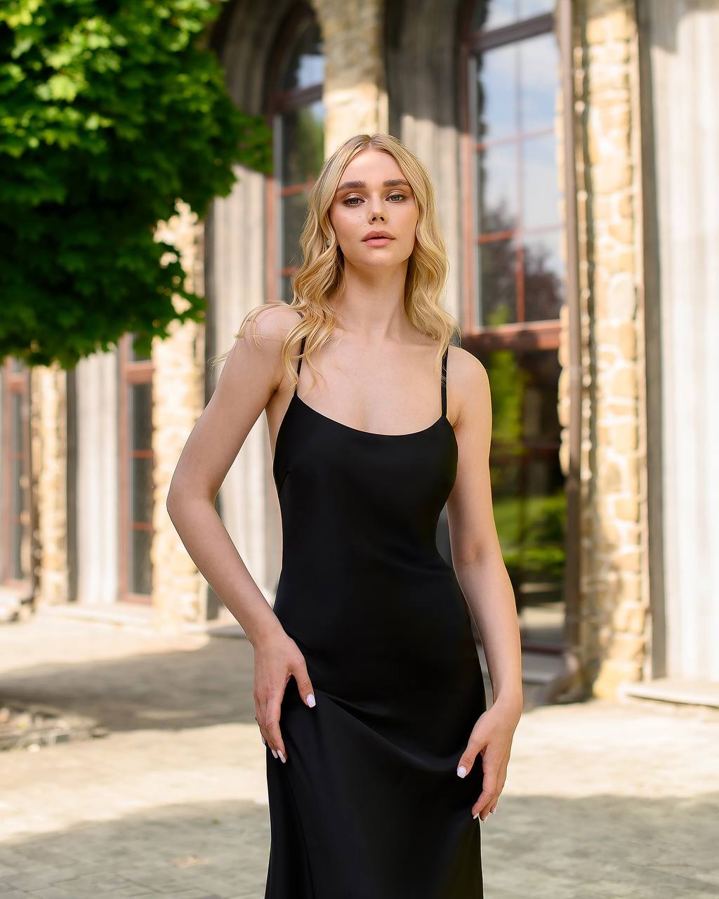 Woman wearing a black dress standing outdoors with classical architecture in the background