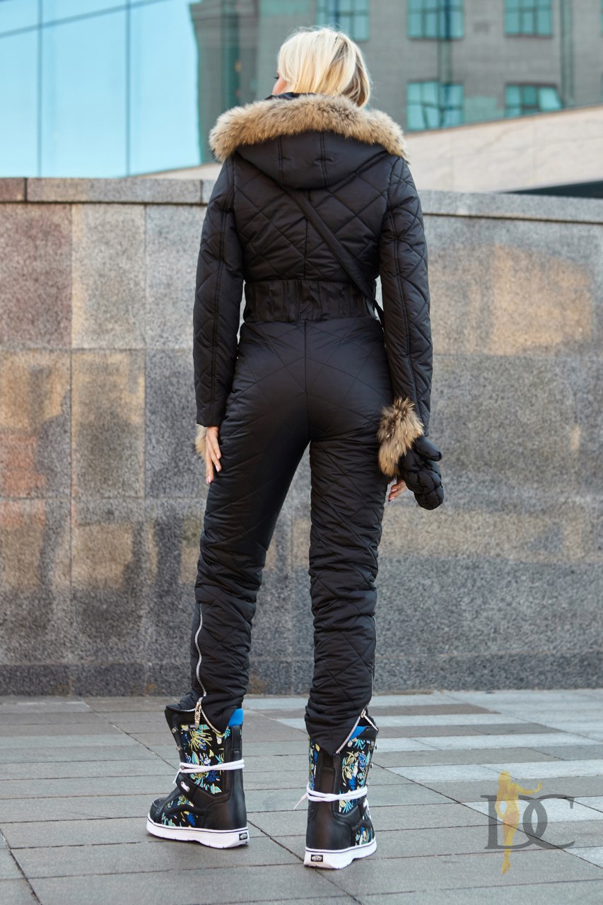 Person wearing a black winter outfit with fur trim in an urban setting