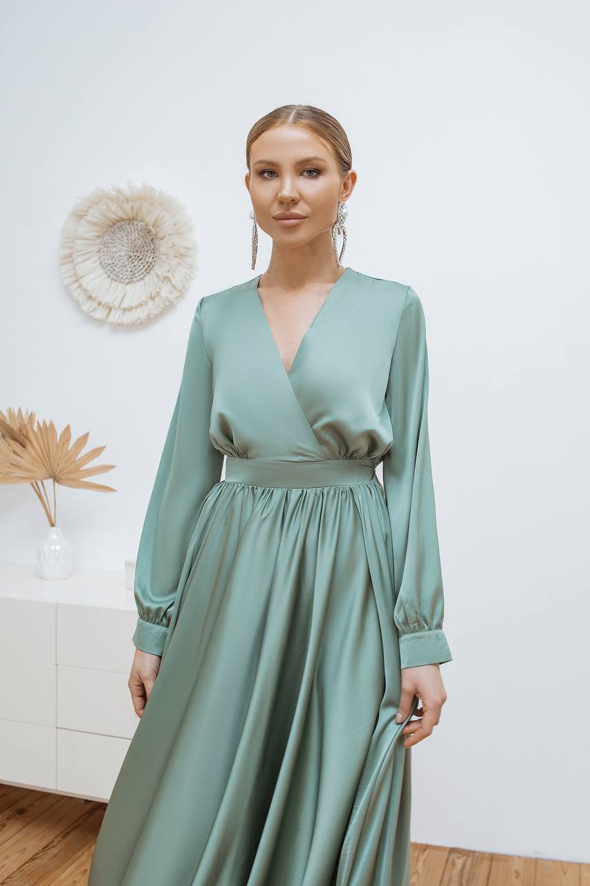 Woman wearing a light green dress with long sleeves in a minimalistic setting.
