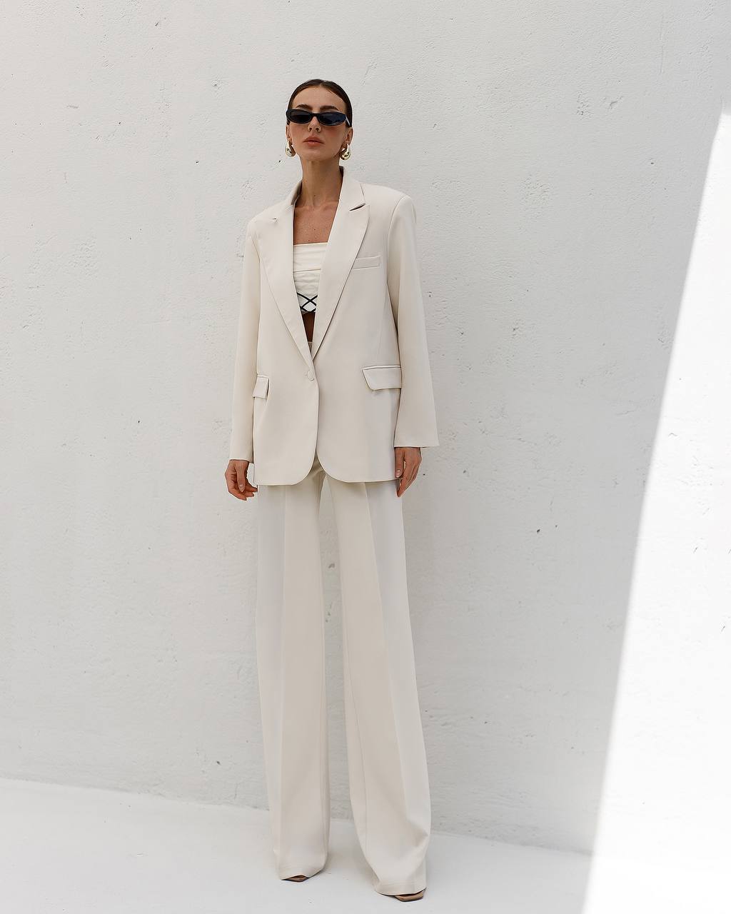 Person wearing a white suit against a plain background